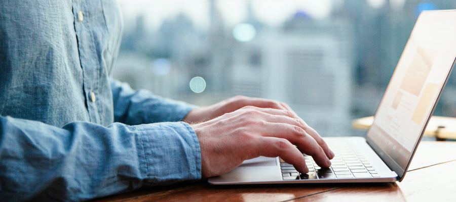 Image of a mans hands on a laptop keyboard.